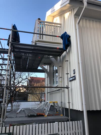 Ny balkong med vitt räcke på ett hus med vit panel.